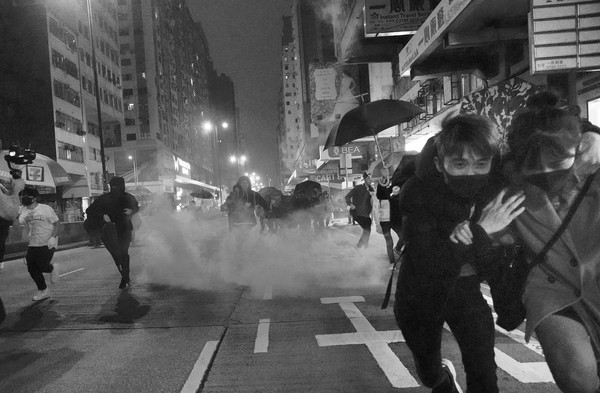 새해 첫날인 1일 새벽 홍콩 시내에서 시위 참가자들이 경찰이 쏜 최루탄을 피해 달아나고 있다. 사진 / AP
