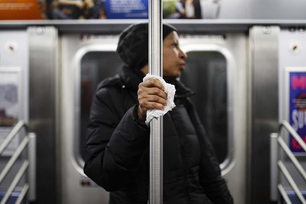 뉴욕 지하철에서 지난 19일 한 여성이 객차 내 손잡이를 휴지로 감싸 쥐고 있다. 뉴욕은 신종 코로나바이러스 감염증(코로나19) 미국 내 최대 확산지다. 뉴욕=AP