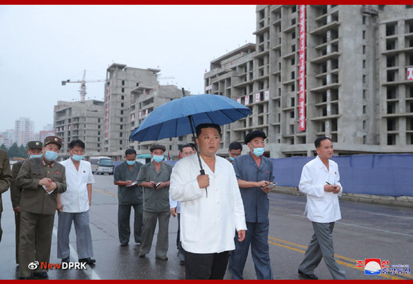 김정은 위원장이 보통강 강안 다락식 주택구 건설현장을 시찰하는 가운데 우산을 직접 들고 있다. 사진=NEW DPRK
