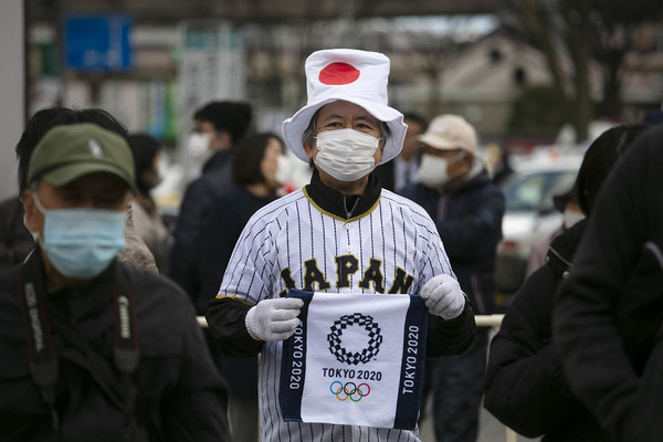 24일 일본 후쿠시마에서 올림픽 성화가 일반에 공개돼 사람들이 모여든 가운데 일본 국기 모양의 모자를 쓴 한 남성이 올림픽 기념 수건을 들고 있다. 후쿠시마=AP