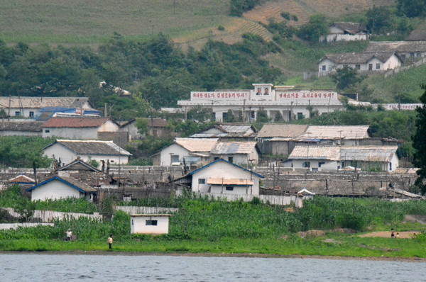 북한과 중국의 국경인 압록강변 한 마을에 최고지도자 사진이 걸려 있다. 사진=DB