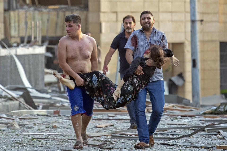 4일(현지시간) 레바논 수도 베이루트 항구에서 대규모 폭발사고가 일어나 시민들이 한 부상 여성을 옮기고 있다. 폭발로 거대한 버섯구름이 떠 오르고 항구 상당 부분이 파괴됐으며 시내 곳곳의 건물이 부서지면서 유리와 문짝 등 파편으로 많은 부상자가 생겼다. 하마드 하산 레바논 보건장관은 최소 50명이 숨지고 약 2800명이 다쳤으며 사망자는 더 늘어날 전망이라고 밝혔다. / 베이루트=AP