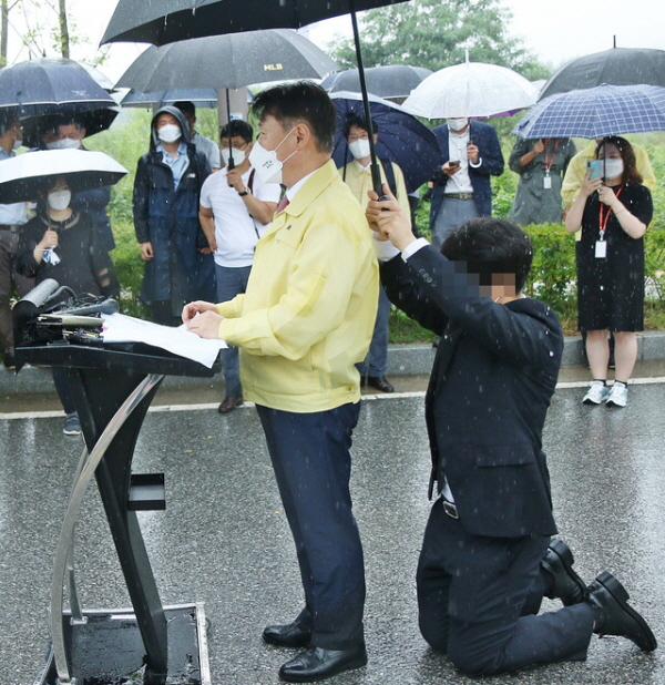 강성국 법무부 차관이 27일 아프간 특별입국자 초기 정착 지원을 발표하는 브리핑을 하는 동안 한 직원이 뒤쪽에 무릎을 꿇고 우산을 받쳐주고 있다. 사진=뉴시스