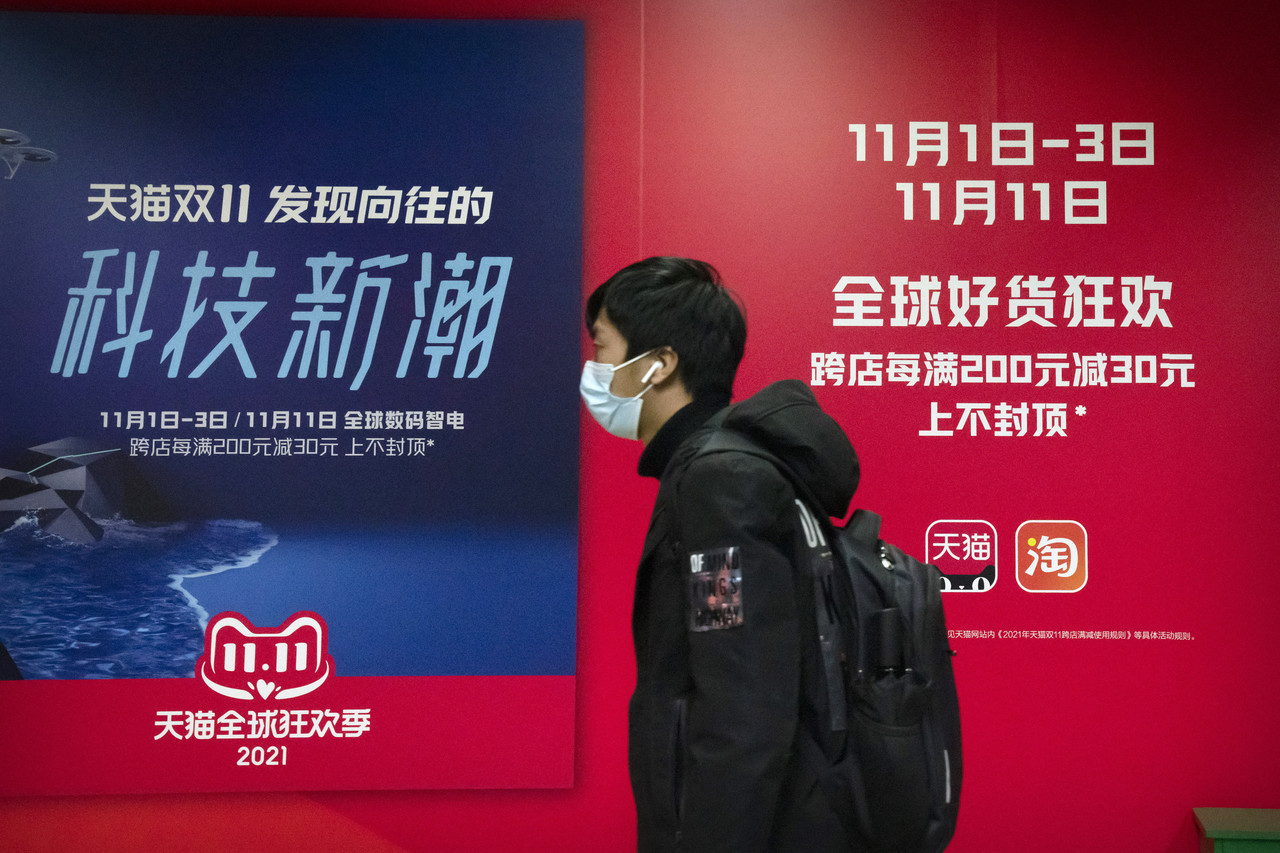 중국 독신자의 날(광군제)인 지난 11일 베이징의 한 지하철역에서 마스크를 쓴 한 시민이 중국의 전자상거래업체 알리바바가 소유한 온라인 쇼핑 플랫폼 '티몰'의 광고판 앞을 지나가고 있다. 중국 최대의 쇼핑 축제인 광군제가 정부의 규제 강화로 올해는 조용한 분위기를 보이는 것으로 알려졌다. 사진=AP