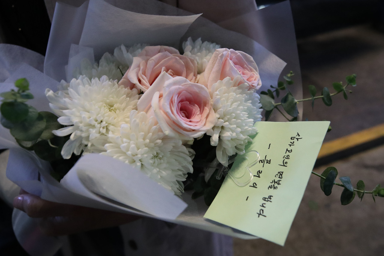 30일 오후 서울 용산구 이태원 압사 사고 인근에 마련된 추모공간에서 한 시민이 헌화할 꽃을 들고 추모하기 위해 대기하고 있다. 사진=뉴시스