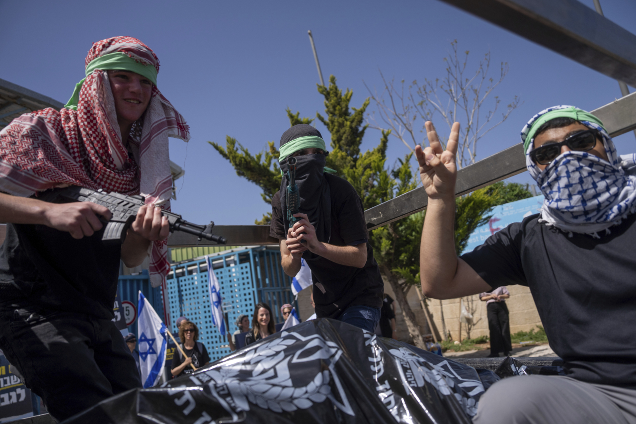 하마스 무장세력의 복장을 한 이스라엘 시위대가 지난 3일(현지시각) 예루살렘에 있는 유엔 팔레스타인 난민구호기구(UNRWA) 본부 입구에서 시위하고 있다. 예루살렘=AP